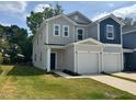 Modern two-story townhouse with gray and blue siding, a garage, and a green lawn at 10517 Brookside Reserve Rd, Raleigh, NC 27614
