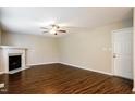 A cozy living room with a fireplace, ceiling fan, and rich wood-look floors at 107 Kimeo Way, Garner, NC 27529
