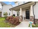 Inviting front porch with brick accents, decorative plants, and a black front door at 110 Gallery Park Dr, Franklinton, NC 27525