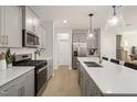 A modern kitchen with stainless steel appliances, light wood floors, and quartz countertops at 1215 Everton Ave, Durham, NC 27703