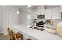 Modern kitchen featuring a large island with a sink, white cabinets, and stainless steel appliances at 1515 Tamarisk Ln, Durham, NC 27703