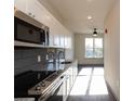 Modern kitchen featuring stainless steel appliances, granite countertops, and dark gray tile backsplash at 2226 Gathering Sq Ct, Fuquay Varina, NC 27526