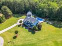 Expansive property with a beautiful blue house, well manicured lawn, pool, and detached garage surrounded by lush trees at 227 Paraggi Ct, Clayton, NC 27527