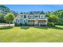 Beautiful two-story blue house with a welcoming front porch and a lush green lawn at 227 Paraggi Ct, Clayton, NC 27527