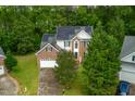 Aerial view of a brick home with solar panels nestled in a lush, green neighborhood at 2305 Bryarton Woods Dr, Raleigh, NC 27606