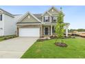 Charming new construction home with a two-car garage, front lawn, and young tree in the front yard at 304 Ford Meadows Dr, Garner, NC 27529