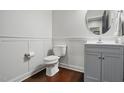 Clean half bathroom with white wainscoting, modern fixtures, and wood flooring at 369 Roberts Ridge Dr, Cary, NC 27513