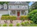 Inviting front porch with a bright red door, classic white columns, and mature hedges for privacy at 5 Providence Ridge Ln, Durham, NC 27713