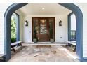 Inviting front porch with stone flooring, wooden benches, craftsman columns, and a stylish wooden door at 523 Vick Ave, Raleigh, NC 27612