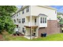A back view reveals a small patio, a balcony, and a well-manicured lawn surrounded by mature trees at 5503 Silver Moon Ln, Raleigh, NC 27606
