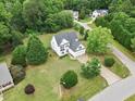 Aerial view of a white two-story home with a large lot in a wooded neighborhood at 5608 Scottish Hills Dr, Holly Springs, NC 27540