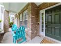 Inviting front porch featuring a brick facade, ample natural light, and cozy Adirondack chairs for relaxing at 9164 Wooden Rd, Raleigh, NC 27617