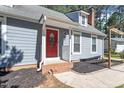 Beautiful front porch with gray siding, a red front door, and brick steps at 111 Mcdole Cir, Cary, NC 27511