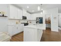 Bright, modern kitchen with white cabinets, an island, stainless steel appliances, and a pantry at 1112 Prewitt Ranch Dr, Holly Springs, NC 27540
