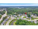 Wide aerial shot of residential neighborhood surrounded by lush greenery, a pond and winding roads at 208 Cecelia Ct, Cary, NC 27519