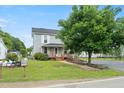 A two-story home with a covered front porch, ramp access, and a large tree in the yard at 2527 Ossipee Front St, Elon, NC 27244