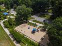 Overhead view of community playground featuring swings, slides, and a soft ground covering, with parking nearby at 519 W Raleigh St, Siler City, NC 27344