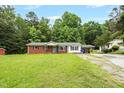 Inviting single-story house with a brick and white exterior, carport, and green front lawn at 5805 Craig Rd, Durham, NC 27712