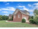 Lovely brick home with attached garage, surrounded by lush greenery, set against a vibrant blue sky at 7800 Twin Pines Way, Fuquay Varina, NC 27526