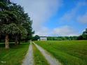 Scenic driveway view of the two-story farmhouse nestled on sprawling acreage at 8365 Aaron Creek Church Rd, Oxford, NC 27565