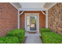 Home's entryway features a charming brick surround, pristine glass door, and manicured bushes at 8404 Saltwood Pl, Raleigh, NC 27617