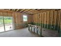 Unfinished interior with stud walls, sliding glass doors opening to the yard, and a window at 91 Caspian Ct, Lillington, NC 27546