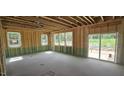 Unfinished interior, featuring stud walls, multiple windows, and sliding glass doors for natural light at 91 Caspian Ct, Lillington, NC 27546