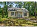 Cozy yellow home with shuttered windows and covered entry, nestled among lush green trees at 940 Hill St, Rocky Mount, NC 27801