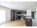 Modern kitchen featuring stainless steel appliances, dark cabinetry, granite countertops, and light wood floors at 103 Hampshire Pl, Kenly, NC 27542