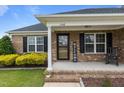 Inviting front porch with brick accents, a welcoming door, and decorative black shutters at 106 Lockwood Dr, Cameron, NC 28326