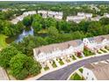 Aerial view of townhouses surrounded by lush greenery and a tranquil pond with a fountain at 109 Ruby Walk Dr, Morrisville, NC 27560