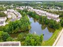 An aerial view showcasing a community with a pond, fountain, mature trees, and townhomes at 109 Ruby Walk Dr, Morrisville, NC 27560