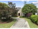 Brick home with a curved driveway, surrounded by mature trees and manicured landscaping providing great curb appeal at 1210 Brooks Ave, Raleigh, NC 27607