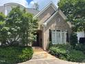 Charming brick home features a well-manicured lawn, mature trees, and a welcoming front porch at 1210 Brooks Ave, Raleigh, NC 27607