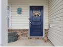 Close-up of a welcoming front door with a decorative wreath, brick accents, and charming mailbox at 13 Toplanders Ter, Gibsonville, NC 27249