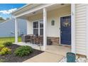 Inviting front porch with comfortable seating, decorative plants, and a charming welcome sign on the door at 13 Toplanders Ter, Gibsonville, NC 27249
