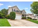 A home boasts a well-maintained lawn and driveway leading to a two-car garage, complemented by mature landscaping at 1428 White Opal Dr, Knightdale, NC 27545