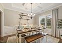 Traditional dining room featuring tray ceiling, chandelier, wainscotting, and natural light from a window at 187 Farrah-Shea Way, Angier, NC 27501