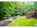 Expansive backyard featuring lush greenery, a wooden deck with stairs, and a well-maintained garden area at 215 Collinson Dr, Chapel Hill, NC 27514