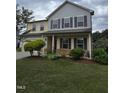 Two-story home with manicured lawn, covered front porch, stone accents, and garage at 2511 Dalmahoy Ln, Fuquay Varina, NC 27526