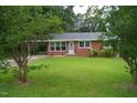 Charming brick home with a well-kept lawn, framed by lush trees, and showcasing blossoming bushes at 2626 Crestline Ave, Raleigh, NC 27603