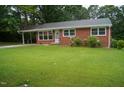 Traditional brick home featuring a well-manicured lawn, a covered carport, and blossoming bushes at 2626 Crestline Ave, Raleigh, NC 27603