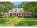 Charming brick home featuring a manicured lawn, lush landscaping, and a welcoming front porch at 300 Bordeaux Ln, Cary, NC 27511