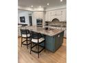 Kitchen island with a stone countertop, seating, and modern appliances in an open layout at 300 Bordeaux Ln, Cary, NC 27511