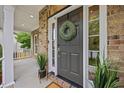 Close-up of front door with wreath, sidelights, potted plants, and covered porch at 4 Pickard Pl, Durham, NC 27703