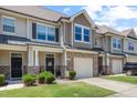Attractive townhome featuring stone accents, a one-car garage, and a welcoming front porch area at 7807 Elmshire Way, Raleigh, NC 27616