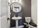 Powder room featuring a pedestal sink, oval mirror, and dark gray paint creating a sleek and modern atmosphere at 805 Winter Meadow Dr, Wake Forest, NC 27587