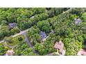 Aerial view of a home nestled among green trees and winding roads in a wooded neighborhood at 1301 King Cross Ct, Raleigh, NC 27614