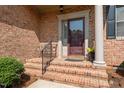 Inviting front entrance with brick steps, a decorative railing, and a classic maroon door at 2014 Muirfield Ct, Elon, NC 27244