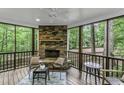 Relaxing screened porch with a stone fireplace, comfortable seating, and views of the serene wooded surroundings at 2325 Old Oak Pl, Hillsborough, NC 27278